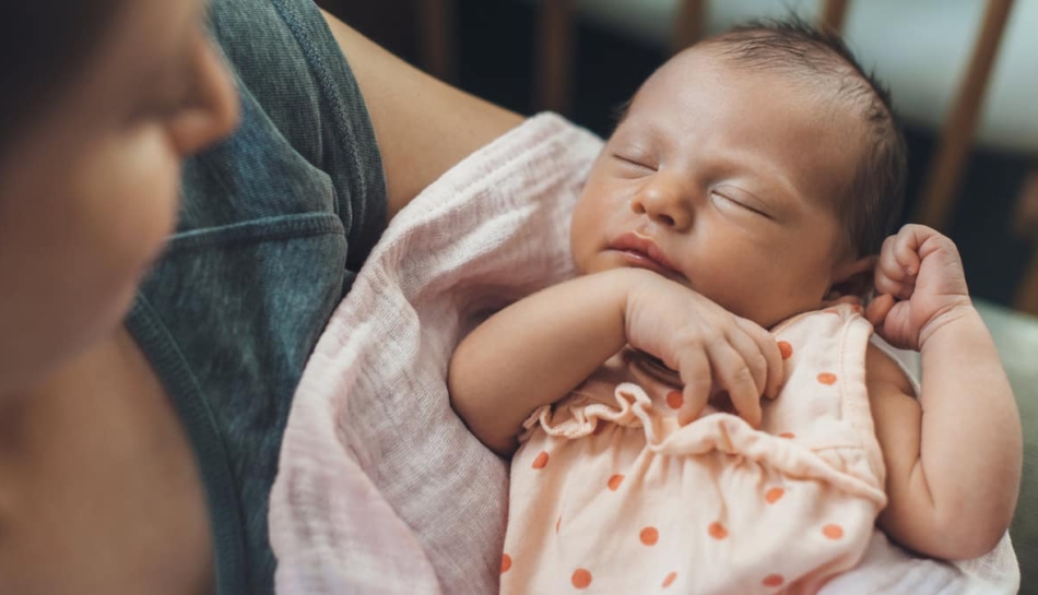 neonato dorme nelle braccia della mamma