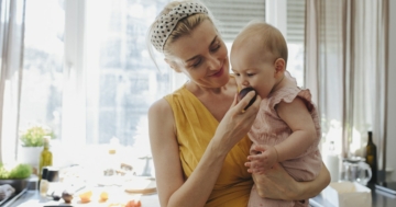 bambina mangia frutta in svezzamento con mamma