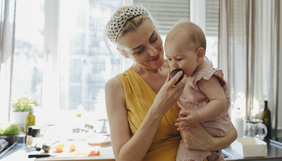 bambina mangia frutta in svezzamento con mamma