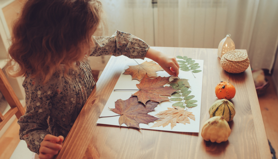 bambina gioca in casa con le foglie