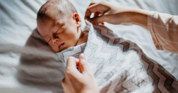 Mamma utilizza la tecnica dello swaddling con il neonato