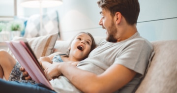 Padre legge un libro per bambini alla figlia