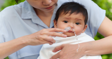 mamma fa un lavaggio nasale al suo bambino