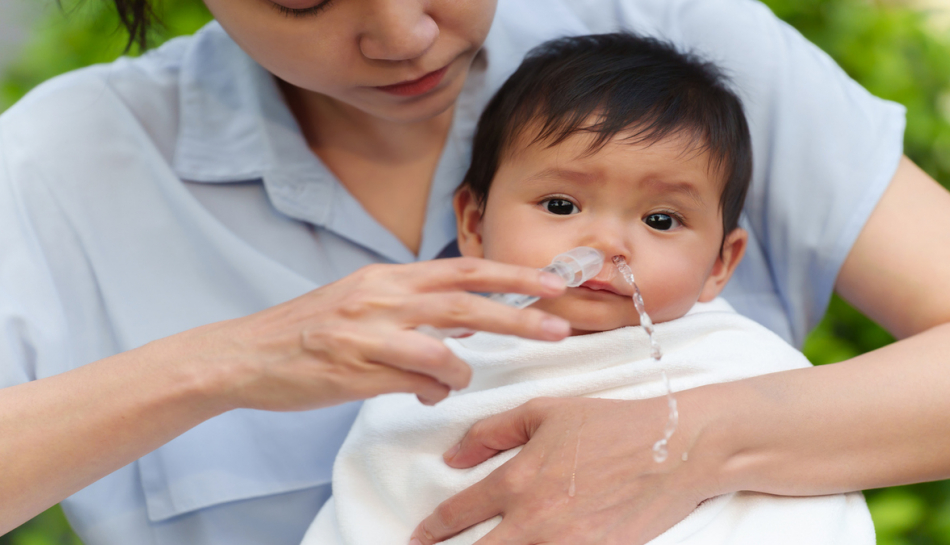 mamma fa un lavaggio nasale al suo bambino