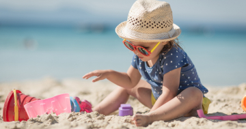 Bambino gioca in spiaggia sotto il sole