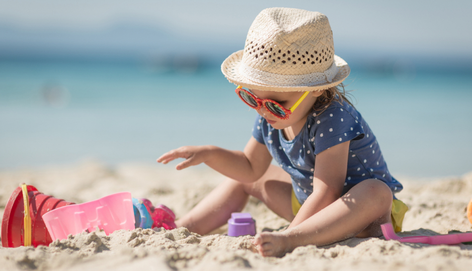 Bambino gioca in spiaggia sotto il sole