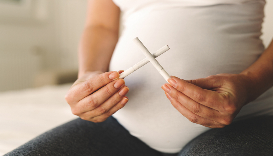 Donna incinta con sigarette intonse in mano
