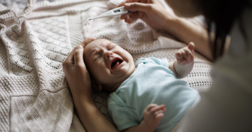 Donna misura la febbre al proprio bambino